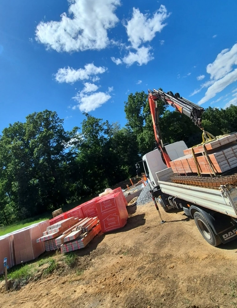 Dodávka stavebního materiálu s hydraulickou rukou na stavbě