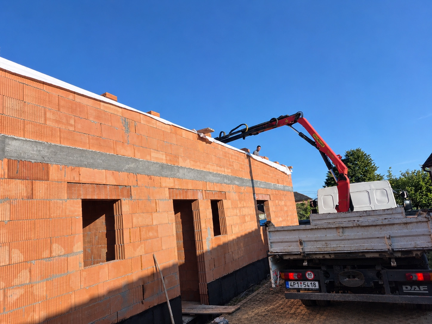 Zdění stěny z cihel s dopravou materiálu jeřábem